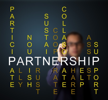 business man writing partnership concept by crossword of relate word such as ally, sustain, help, support, assist, share, etc の写真素材