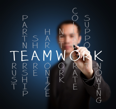 business man writing teamwork concept by crossword of relate word such as trust, partnership, share, collaborate, support, etc の写真素材