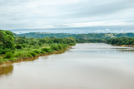 River with lush green river bank and muddy rain water at Polali, Mangalore, Indiaの写真素材