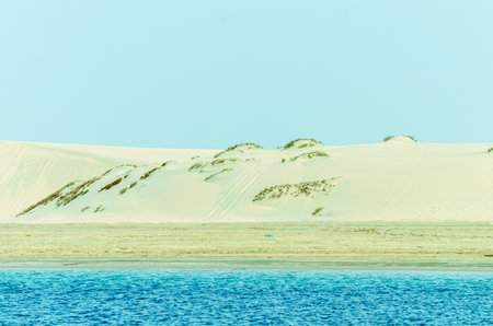 Sand dunes descending into the creek with limestone hills in the background at Al-Adaid Desert in Qatarの写真素材