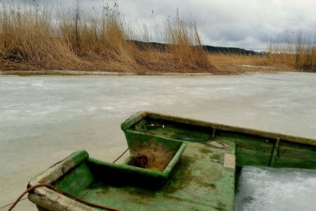A sunken rowing boat lays in the frozen Baltic Sea at the Finnish coast.の素材