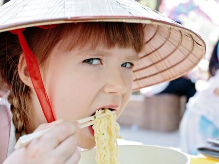 Little girl eating korean style spaghetty  ramen  using chopsticksの写真素材