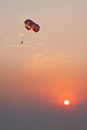 Flight of parachute over sea on sunsetの写真素材