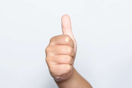 Boy raising one fingers up on hand that is thumb up its shows superb or excellent symbol on white background.の写真素材