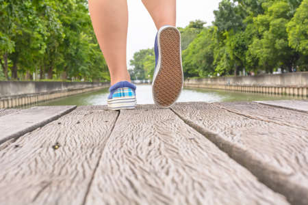 Girl wearing canvas sneakers standing on the wooden bridge.の写真素材