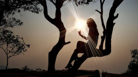 Women's silhouette at sunset on nature background.の写真素材