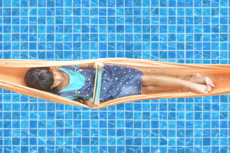 The girl was lying play tablet on the hammock.
