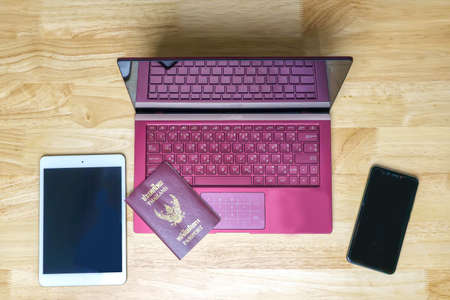Computer notebook laptop with digital tablet, smartphone and passport on wooden desk in business room.の写真素材