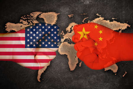 Flags of USA and China on fist hand on a map world background/us china trade war concept.の写真素材
