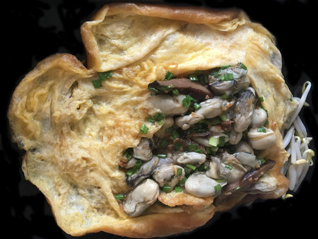 Chinese oyster omelette on a black pan.の写真素材
