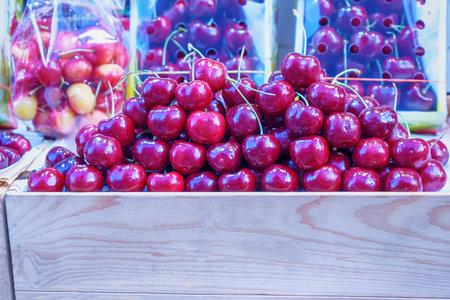 Pile of fresh ripe red cherries in wooden crate at fruit market.の写真素材