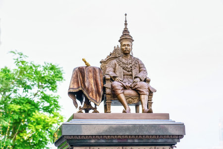 Bronze statue of King Rama V seated on a throne, symbolizing Thai history and culture, photographed in bright daylight.の写真素材