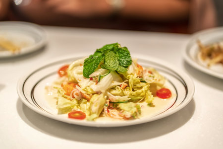 Shallow-depth shot of Thai style shrimp salad with lettuce, herbs, lemongrass and cherry tomatoes topped with fresh mint leavesの写真素材