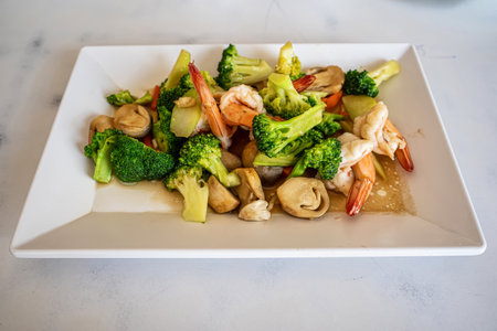 Healthy stir fried broccoli with fresh shrimp and mushrooms served on white square plate.の写真素材