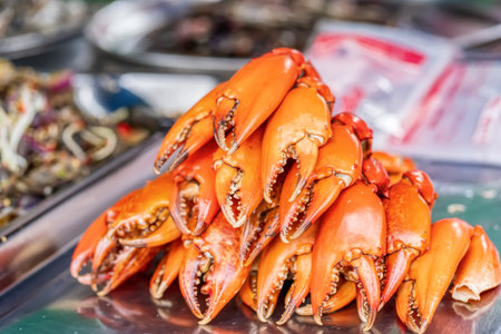 Pile of fresh steamed orange crab claws or paddle crab at seafood market stall.の写真素材