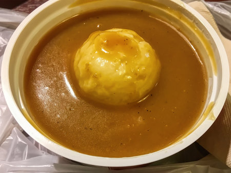 A bowl of smooth mashed potato topped with brown gravy sauce in a takeaway container.の写真素材