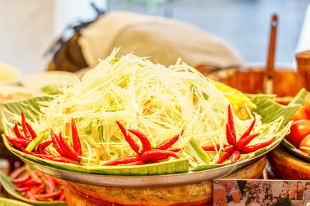 Pile of fresh shredded green papaya with red chilies for making traditional Thai spicy salad.の写真素材