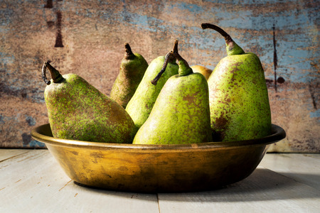pears in copper tray on wooden tableの写真素材