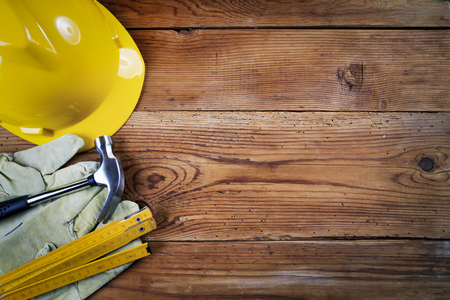 hammer, protective gloves, folding meter and yellow safety helmet on wooden backgroundの写真素材