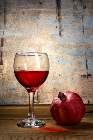 glass of red wine and pomegranate on wooden table の写真素材