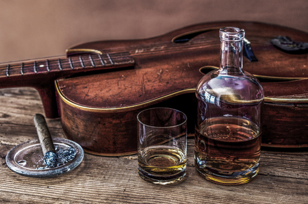 bottle, glass of whiskey, cigar and old guitarの写真素材