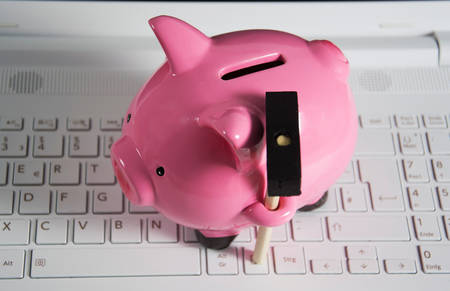 a pink piggy bank on a laptopの写真素材