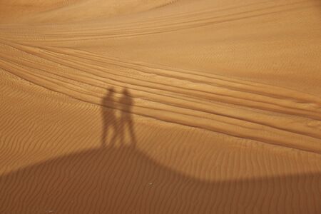 shadows of couple in desert near Dubaiの写真素材