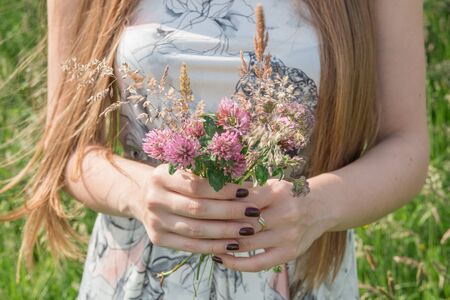 Portrait of beautiful blond woman in dress with summer flowersの写真素材