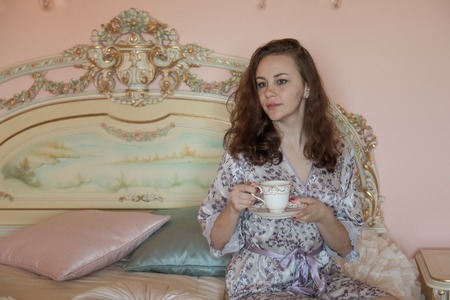 Young beautiful woman with tea in bed in the morningの写真素材