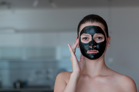 Young beautiful woman with a black mask for the face in the bathroomの写真素材