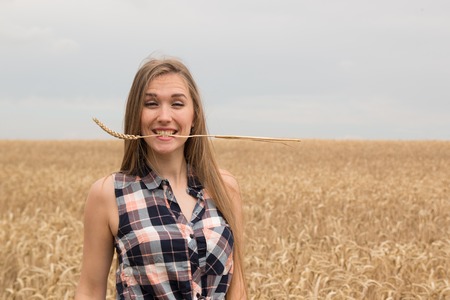 Happy young beautiful woman in golden wheat field in the summerの写真素材
