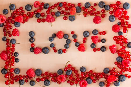 LOVE words berries in frame on light wooden backgroundの写真素材