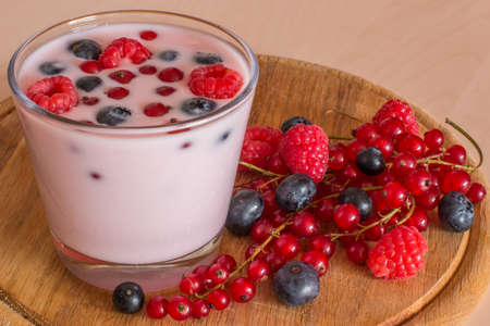 Yogurt with forest berries in bowl on wooden tableの写真素材