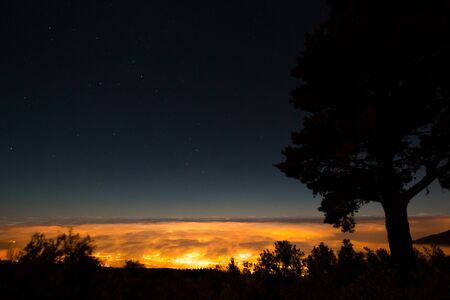 View over clouds in city light in mountain, Tenerife, Spainの写真素材