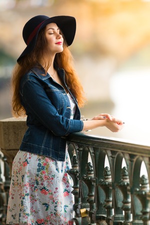 Portrait of the beautiful fashionable girl with hat on embankment in summer dayの写真素材