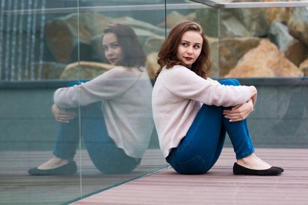 Reflection of cute fashionable girl in modern glass building