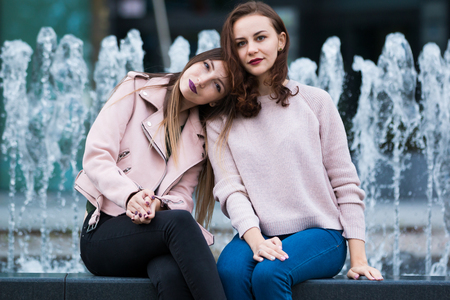 Two beautiful young women having fun next to fountain on street of the city, Pragueの写真素材