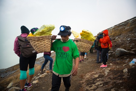 IJEN, INDONESIA - 11.11.2017: Sulfur miner carrying sulfur-laden baskets at Kawah Ijen volcano in Java, Indonesia.のeditorial素材