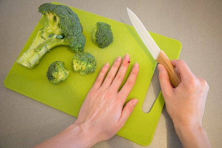 Wounded finger with blood and knife on cutting board with broccoliの写真素材