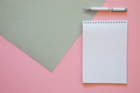 Top view of blank note paper with pen on pink background