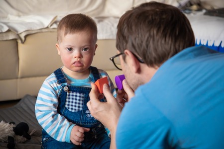Cute baby boy with Down syndrome playing with dadの写真素材