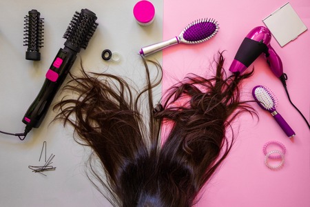 Professional hairdressing tools and brunette hair on pink backgroundの写真素材