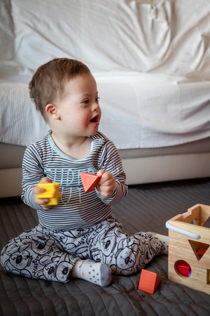 Portrait of cute boy with Down syndrome playing in home living room