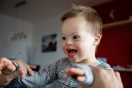 Cute boy with Down syndrome playing with dad on in home living roomの写真素材