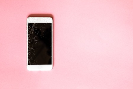 White smartphone with broken screen on pink backgroundの写真素材