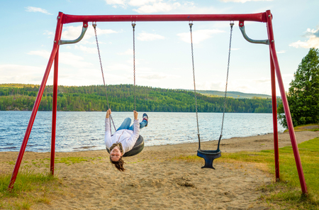Young woman on swing in Oppstrynsvatn lake in the municipality of Stryn in Sogn og Fjordane county in Norwayの写真素材