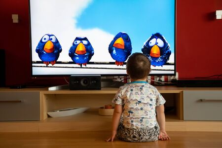 Prague, Czech Republic -18.03.2019: Small boy with Down syndrome watching cartoon on TVのeditorial素材