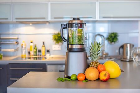 Making green smoothies with blenderat home in kitchen, healthy eating lifestyle conceptの写真素材
