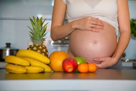 Pregnant woman and different tropical fruits in the home kitchenの写真素材