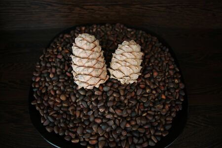 Pine nuts in shells as a background and two whole cedar cones, top view